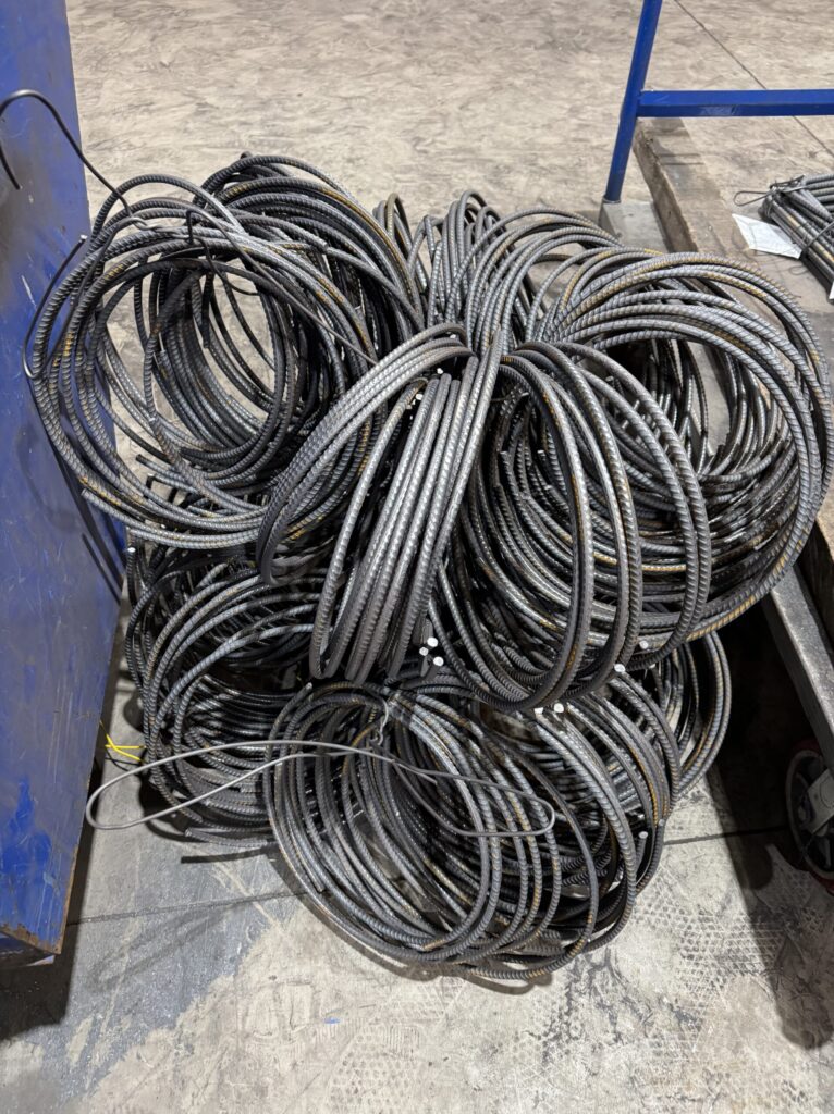 Coiled rebar hoops staged in a fabrication shop for concrete reinforcement