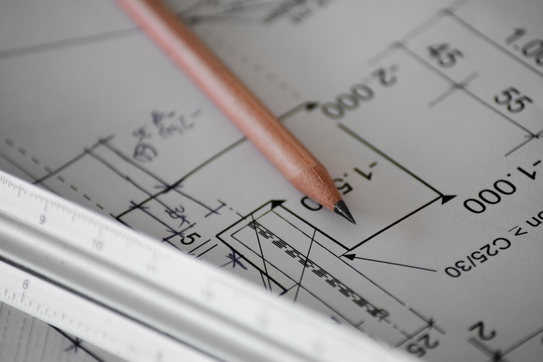 Pencil resting on architectural blueprints with measurements